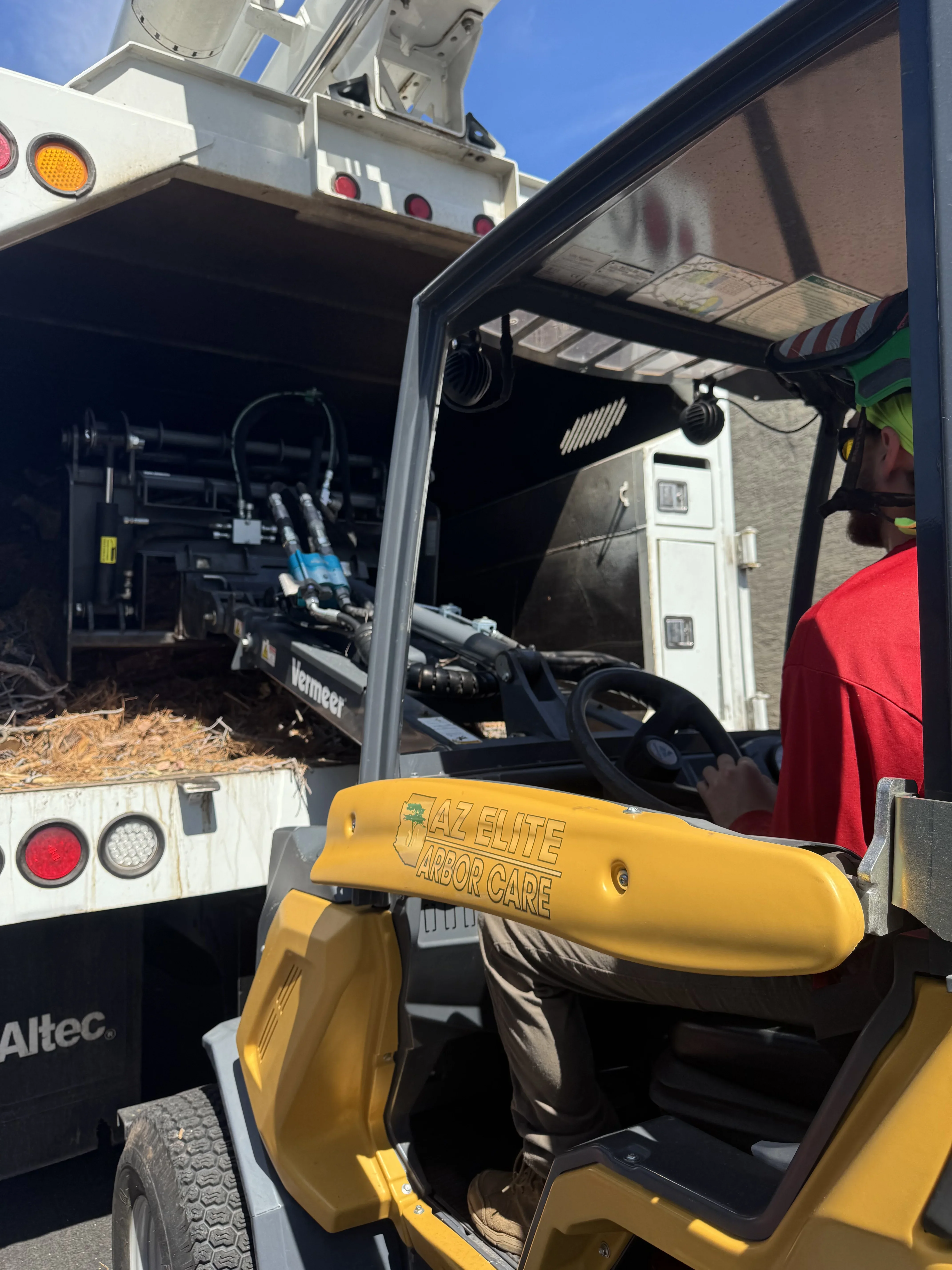 Yellow wood chipper and professional tree service equipment loaded on utility truck